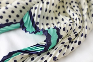 Détail du foulard plissé en soie avec pois marine et rayures contrastées vertes