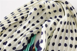 Vue détaillée du foulard plissé à pois crème avec bordure contrastée bleu marine et vert