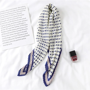 Détail d'un foulard en soie plissé à pois bleu marine et bordure géométrique