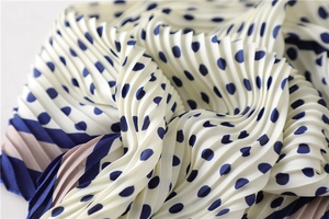 Vue macro d'un foulard plissé en soie avec des pois marine et des bords rayés