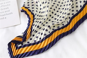Gros plan d'un foulard en soie plissé à pois avec bordures de couleur contrastée