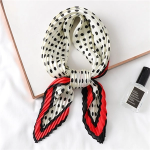 Vue détaillée du foulard en soie crème à pois noirs avec des bords rouges ondulés