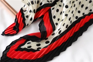 Vue détaillée du foulard plissé à pois avec plis accordéon et bordure rouge et noire