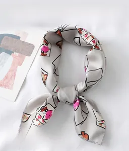 Close-up of silk-like scarf with red heart patterns tied in a stylish knot on white fabric