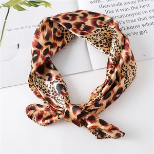 Classic leopard print satin silk scarf tied in a bow on a stylish magazine background