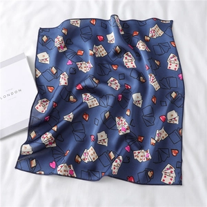 Navy blue silk-like scarf featuring heart and poker card patterns laid on a white fabric