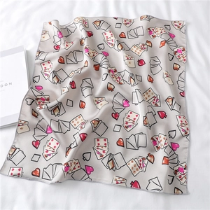 Detail of satin square scarf featuring heart and playing card patterns on grey fabric