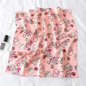 Pink satin scarf with heart playing card patterns on a soft white draped background