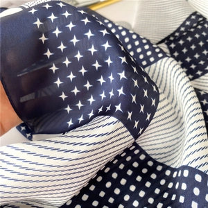 Macro shot of silk texture neckerchief with blue and white geometric patchwork patterns
