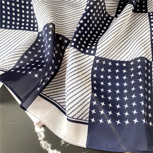 Detail of silk scarf showing star pattern and fine stitching on navy blue fabric