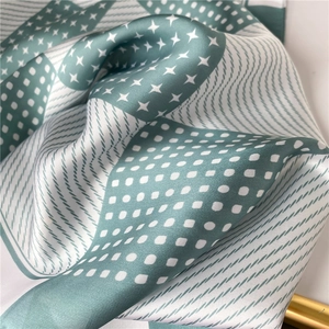 Close-up of mint green silk scarf with polka dots, stripes and geometric patterns