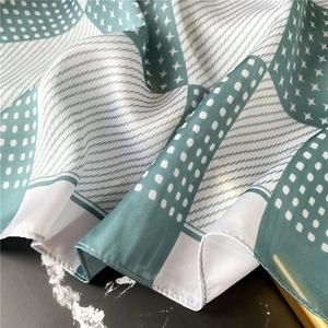 Detail of forest green silk scarf with geometric polka dots and fine rolled hem