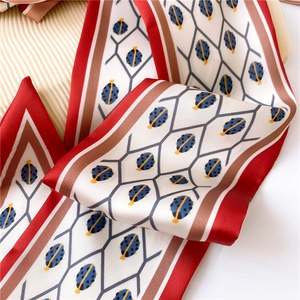 Close-up of ladybug pattern and silky texture on a geometric double-sided skinny scarf