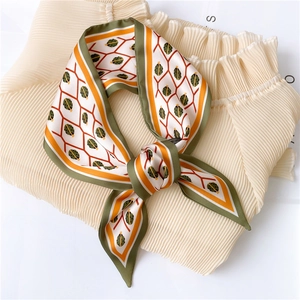 Detail of silk-like neckerchief with green leaf patterns and geometric orange grid design