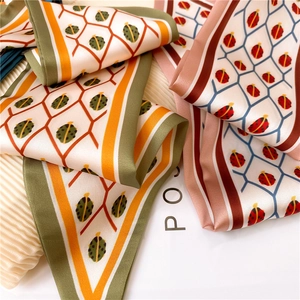 Close-up of silk neck scarves featuring ladybug prints and geometric honeycomb patterns