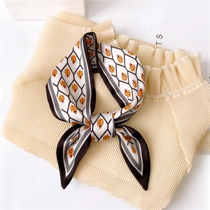 Silk-like ladybug scarf with geometric grid pattern tied as a bow on beige top