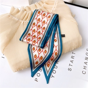 Detail of blue-edged silk scarf with orange ladybug pattern and 100% polyester care label