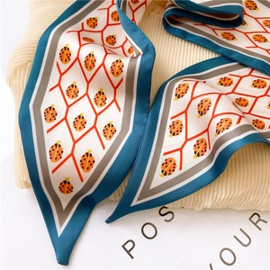 Detailed macro view of ladybug print silk twilly scarf layered on pleated fabric surface