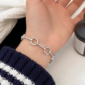 Detailed close-up of a silver-colored chain bracelet with micro-set zircon stones on the wrist