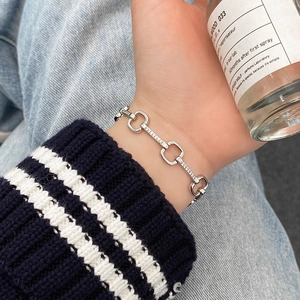 Close-up of a silver geometric chain bracelet with micro-pave zircons on a model's wrist