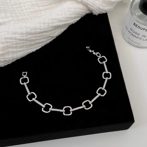 Detail of silver chain bracelet with polished geometric links and micro-pave zircons