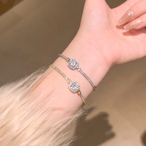 Close-up of gold and silver square halo bracelets with sparkling round zircon stones