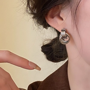 Close-up of triple layered silver hoop earrings worn on ear with polished finish