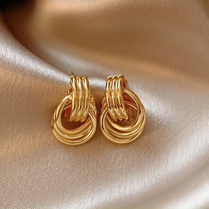 Close-up of golden multi-layered circular stud earrings on champagne satin fabric