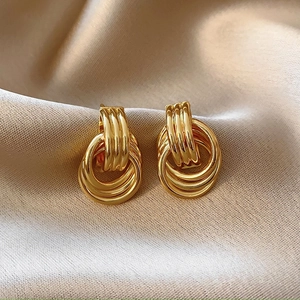 Close-up of golden multi-layer hoop earrings on champagne silk fabric background