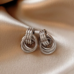 Close-up of interlocking silver layered hoop earrings on champagne silk fabric
