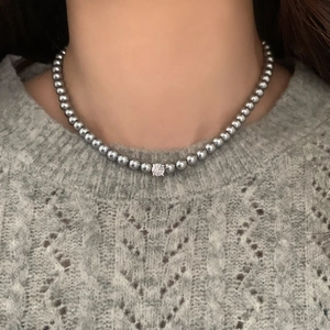 Collier élégant en perles grises avec une pierre centrale en zircon porté par un mannequin