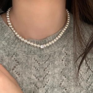 Collier de perles élégant avec pendentif en cristal sur un mannequin en pull gris