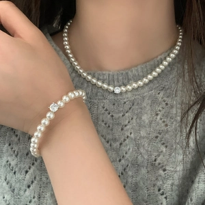 Détail de l'ensemble collier et bracelet en perles avec zircons au design minimaliste
