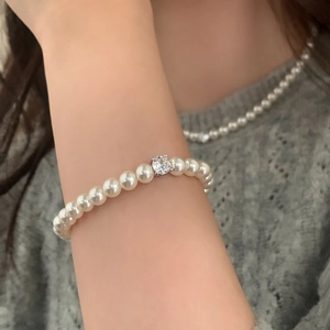 Détail d'un bracelet de perles avec une pierre précieuse scintillante sur le poignet