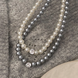 Vue détaillée de colliers de perles élégants avec cristaux brillants sur fond tricoté