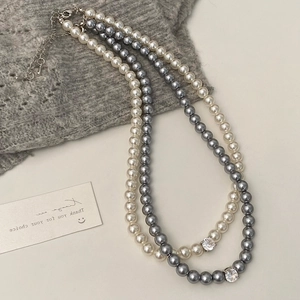 Détail de colliers de perles blanches et grises avec des pendentifs en zircon brillant