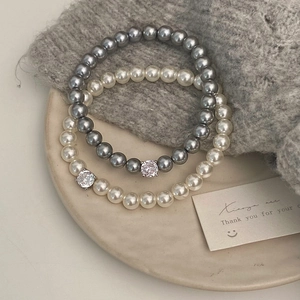 Détail de bracelets de perles blanches et grises élégants avec cristal central