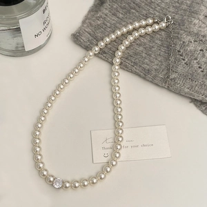 Gros plan d'un collier de perles élégant avec un pendentif en zircone cubique brillant