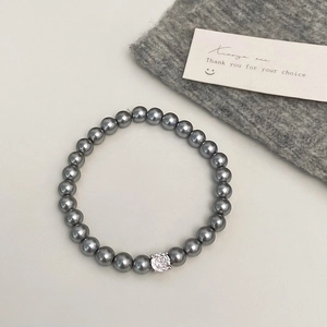 Détail d'un bracelet en perles gris foncé avec un zircon blanc étincelant au centre
