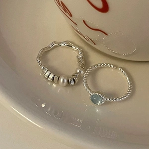 Detailed close-up of S925 silver rings with blue cat eye stone and pearl on a ceramic tray
