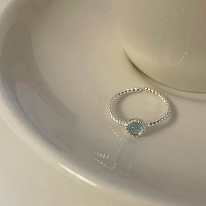 Detail of twisted silver band ring with a round light blue cat eye stone inlay