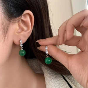 Close-up of zircon earrings with green chalcedony pendants worn on the earlobe