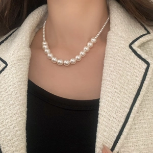Gros plan d'un collier de perles dégradées blanches brillantes porté par un mannequin