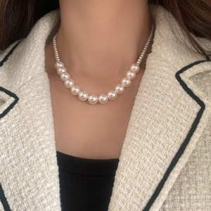 Collier de perles dégradé élégant sur mannequin portant une veste en tweed