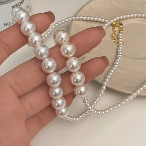 Collier élégant avec perles blanches dégradées et fermoir doré dans un décor chic