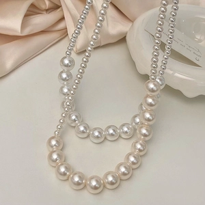 Collier élégant à deux rangées de perles crème sur fond en soie avec plateau céramique