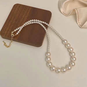Gros plan d'un élégant collier de perles dégradé avec fermoir mousqueton doré et chaîne