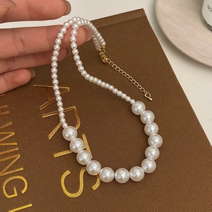 Détail d'un collier de perles dégradées avec fermoir doré et chaîne de réglage ajustable