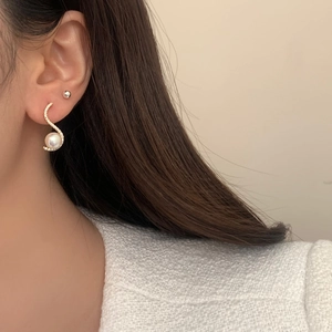 Elegant S-shaped gold earrings with white Mabe pearls and sparkling zircons on model
