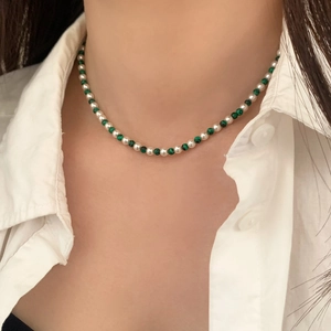 Collier élégant avec perles blanches et perles de malachite verte sur un mannequin